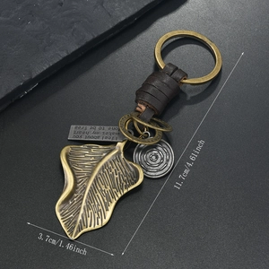 Macro detail of bronze ginkgo leaf keychain with woven leather and engraved metal charms