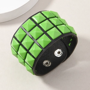 Detail of wide punk leather bracelet with fluorescent green pyramid studs and silver buckles