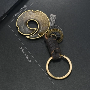Detail view of vintage bronze ginkgo leaf keychain with dark brown woven leather cord