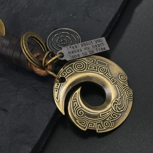 Macro detail of bronze alloy ginkgo leaf charm with leather rope and engraved poem tag