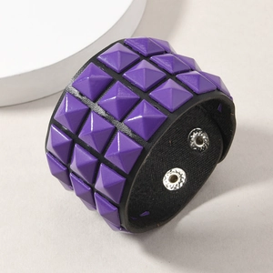 Detail of black leather punk bracelet with four rows of purple pyramid square rivets
