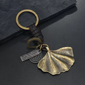 Detail of vintage bronze ginkgo leaf and braided leather strap on a metal keychain