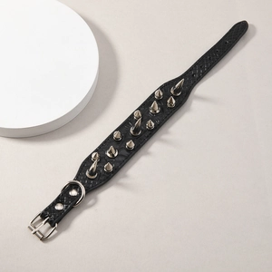 Detalle de pulsera de cuero negro con patrón de serpiente y puntas de metal plateado con remaches