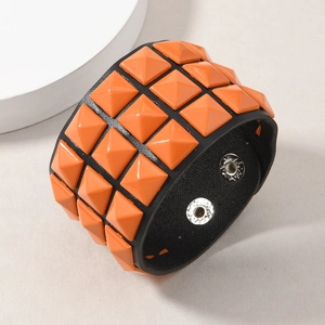 Detail view of triple row orange pyramid studs on a black punk style leather wristband