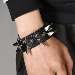 Detalle macro de pulsera de cuero negro punk con tres filas de largas púas de plata metal