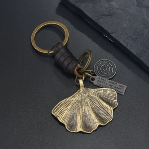 Detail of vintage bronze ginkgo leaf keychain with leather wrap and engraved metal tags