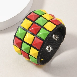 Detail of wide black leather punk bracelet featuring red yellow and green pyramid studs