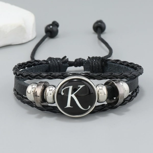 Macro detail of multi-layer black leather bracelet featuring letter K and metal beads