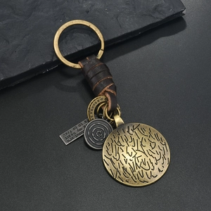 Macro view of vintage bronze ginkgo leaf keychain with leather strap and engraved metal tags