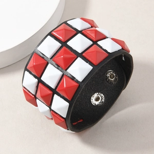 Detail of punk leather bracelet with red and white square rivets and metal snap buttons