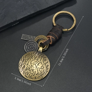 Vintage alloy keychain with woven leather strap and bronze ginkgo leaf charm on dark background