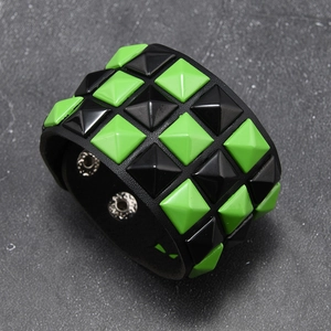 Detail view of punk black leather bracelet with green pyramid studs and snap buttons