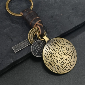 Detail of vintage bronze alloy keychain with woven leather strap and diverse pendants