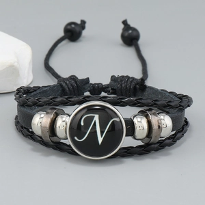 Close-up of multilayer braided leather bracelet with silver beads and letter N glass charm