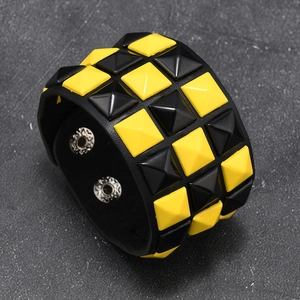 Detail of punk leather bracelet with black and yellow pyramid studs and metal snap buttons