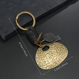 Detail of vintage punk keychain with bronze charms, woven leather, and size marking