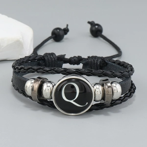 Macro detail of multilayer leather bracelet with letter Q glass pendant and metal beads