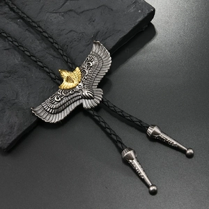 Λεπτομέρεια bolo tie με χρυσό αετό και ασημένια φτερά σε πλεγμένο δερμάτινο κορδόνι