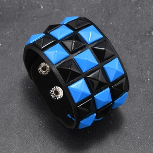 Detail of punk leather bracelet showing black and blue square pyramid studs and snap buttons