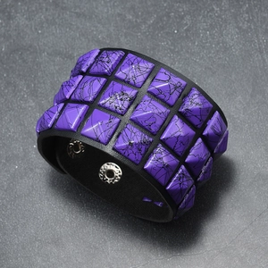 Detail view of purple splatter pyramid studs on a wide black leather punk rock bracelet