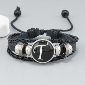 Detail of multi-layer leather bracelet featuring letter T charm and woven rope texture