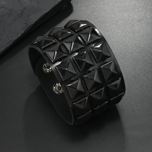 Detailed view of wide punk leather bracelet with three rows of black pyramid studs