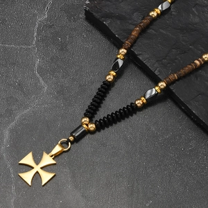 Vue détaillée du pendentif croix de Malte dorée sur un collier de perles vintage