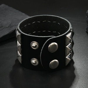 Close-up of black punk leather bracelet with triple-row silver pyramid studs and snap buttons