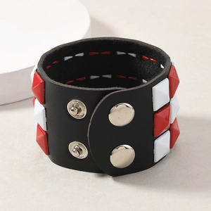 Detail of black leather punk bracelet with red and white pyramid studs and metal snaps