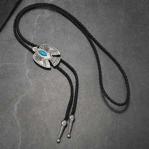 Detail of vintage eagle bolo tie with turquoise inlay and braided leather cord on stone
