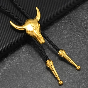 Détail de la cravate bolo tête de taureau dorée avec cordon tressé noir sur fond texturé