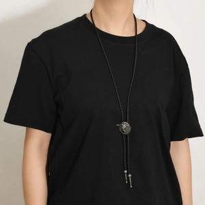 Detail einer silbernen Western-Bolo-Tie mit Stierkopf auf einer schwarzen Kordel