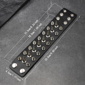 Détail d'un bracelet punk en cuir noir orné de trois rangées de pointes métalliques argentées