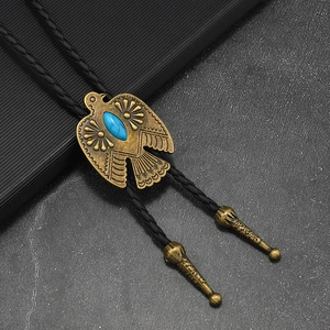 Close-up of golden eagle bolo tie with turquoise stone and braided black leather cord