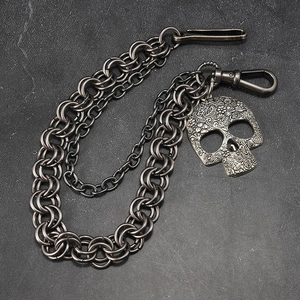 Double-layered punk pants chain with vintage metal skull pendant on a stone background