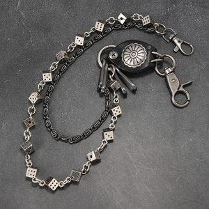 Punk metal wallet chain with dice charms and leather accent on an industrial surface