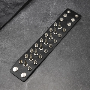 Détail du bracelet punk en cuir noir orné de trois rangées de clous et pointes en métal argenté