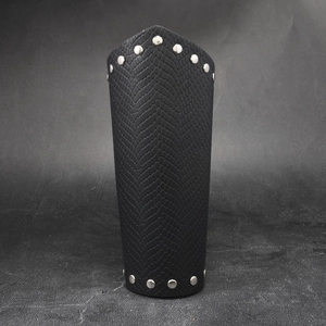 Macro detail of black snake-textured leather bracer with silver metal rivet studs