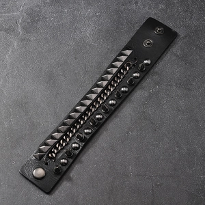 Punk leather bracelet with metal studs, spikes and chains on grey stone texture