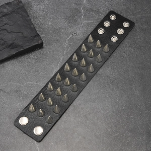 Macro shot of black punk leather bracelet featuring triple rows of metal spikes and studs