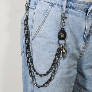 Detail of layered punk trousers chain with leather eagle crest and animal claw pendant