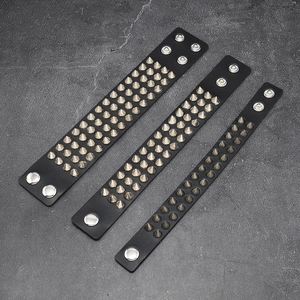 Detail of three leather punk bracelets featuring different rows of silver metal spikes