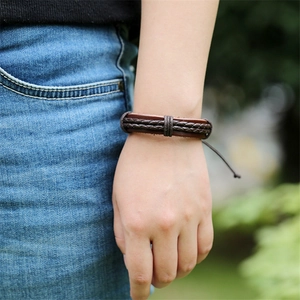Dettaglio macro di un bracciale in pelle marrone multistrato indossato alla luce naturale