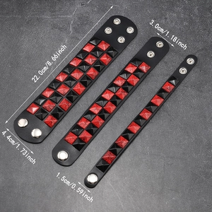 Dreiteiliges Punk-Lederarmband-Set mit rot-schwarzen Pyramiden-Nieten auf Steinhintergrund
