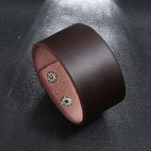 Detail showing the dark brown wide leather cuff with two silver metallic snap buttons
