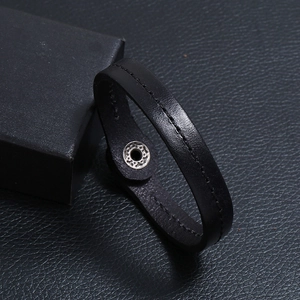 Detail of black leather bracelet with white stitching and silver snap button closure