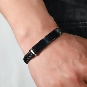 Primer plano de pulsera trenzada de cuero negro con detalles metálicos pulidos y cierres plata