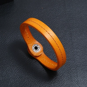 Detail of orange leather bracelet featuring central stitching and silver metal snap button
