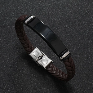 Detalle de una pulsera de cuero trenzado marrón con placa de metal negro y cierre de acero inoxidable