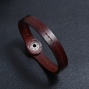 Detail of brown cowhide leather bracelet featuring fine texture and silver snap button